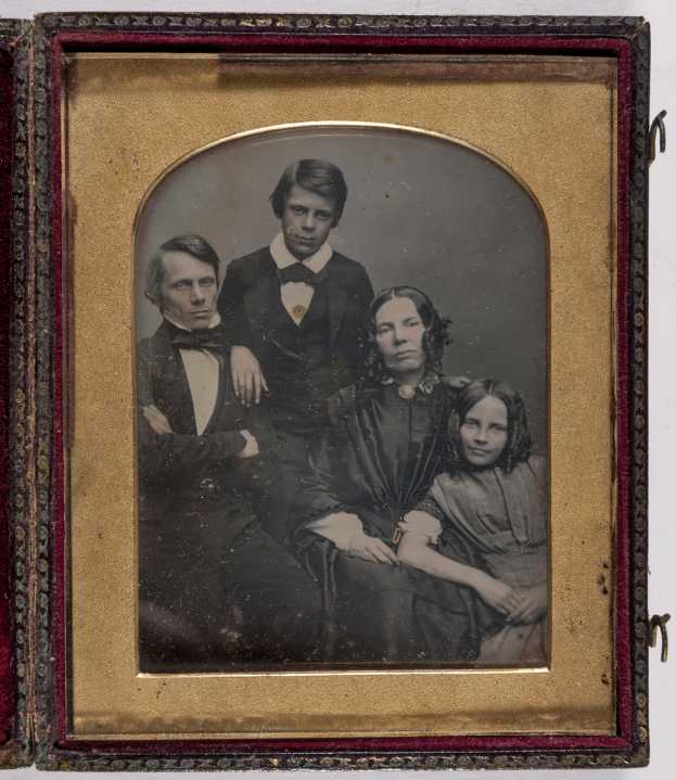 Ein Daguerreotyp einer Familie in formeller Kleidung vor einem weißen Hintergrund.