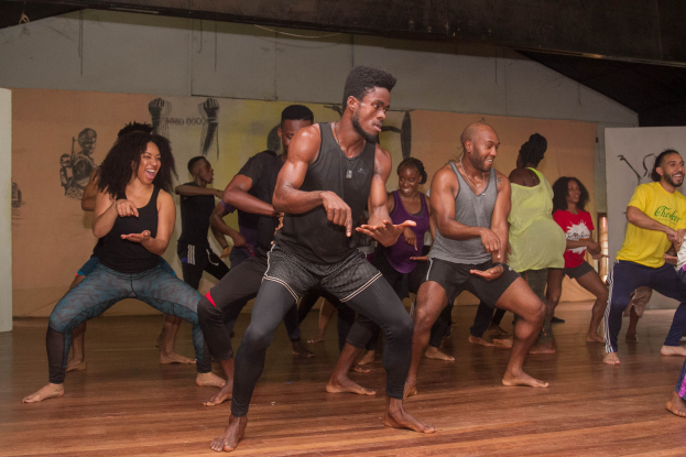 Eine Gruppe von Menschen, die in einem Raum mit Wandgemälden und einer Decke tanzen, wahrscheinlich Teil eines Choreografie-Kurses an der Universität Chicago.