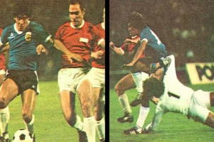 Eine Gruppe von Männern, die Fußball auf einem Feld spielen, wobei einer den Ball tritt und andere versuchen, die Kontrolle zu erlangen, vor einer Tafel in einem Stadion.