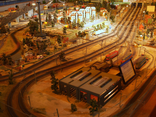 Eine detaillierte Modellbahnausstellung in einem Museum, mit Gebäuden, Bäumen, Schienen, Fahrzeugen und anderen Miniaturstädtelementen.