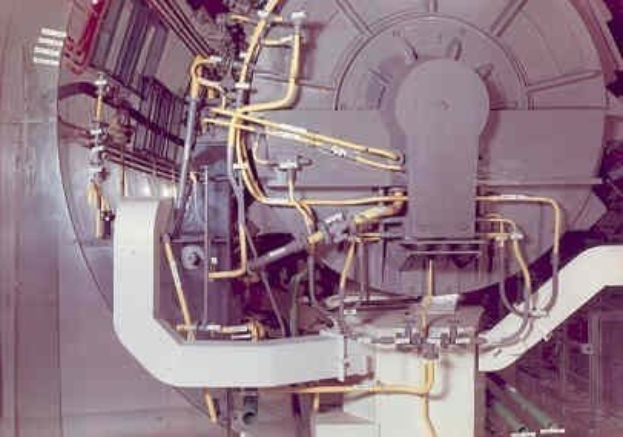 Große industrielle Beschleuniger-Maschine mit mehreren angeschlossenen Komponenten und Kabeln innerhalb eines Gebäudes.