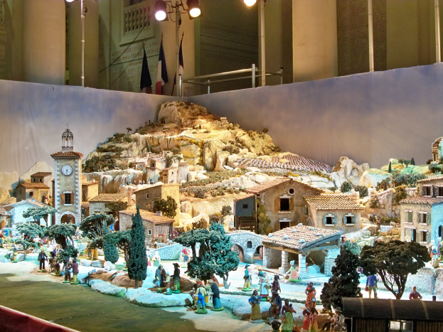 Ein detailliertes Miniatur-Modell einer Krippe in einem Museum ausgestellt, mit Figuren, Strukturen und Beleuchtungselementen unter Museumsbeleuchtung.