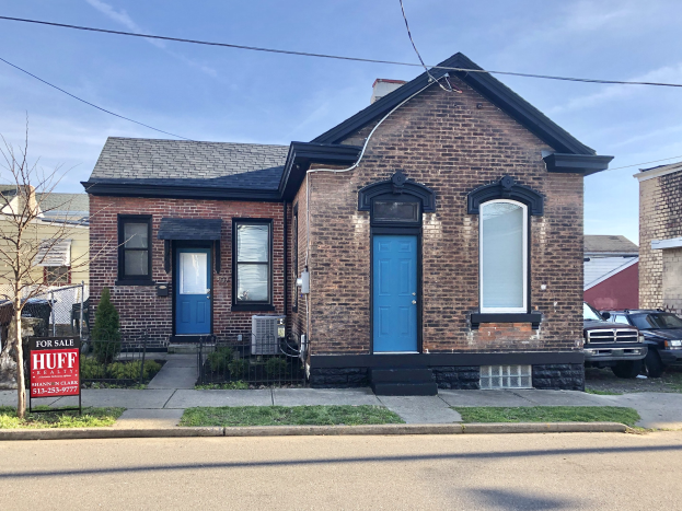 Ein roter Backsteinbau mit einer blauen Tür an einer Straßenecke, mit einem Verleihschild, auf dem "Verwaltungsgebäude zur Miete, Listid 29058910, Standort 5901 S Elmwood Ave Chicago 60618" steht, umgeben von Gebäuden, Bäumen und Fahrzeugen unter einem bewölkten Himmel.