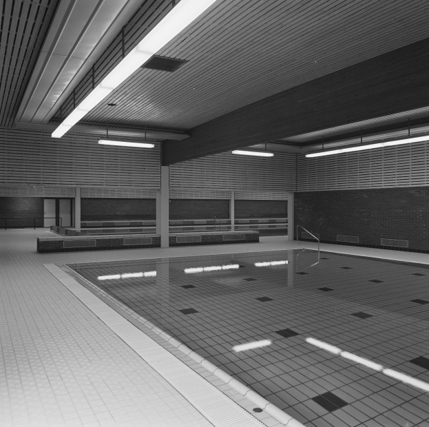 Innenbad mit klarem Wasser, gefliesten Wänden und Boden, Deckenleuchten und einigen umgebenen Gegenständen in einer ruhigen Umgebung.