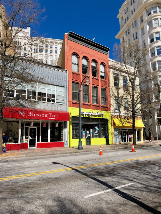 Eine Straße in der Innenstadt von Portland mit hohen Gebäuden, Kraftfahrzeugen, Fußgängern, Straßenlaternen, Absperrkegeln, Bäumen und einem bewölkten Himmel.