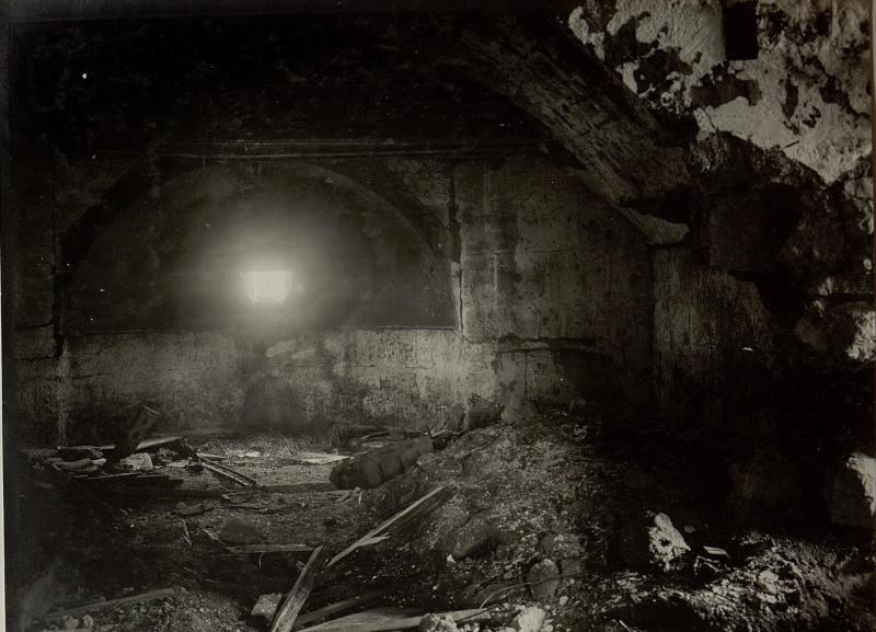 Ein Schwarz-Weiß-Foto eines zerfallenden Tunnels in den Ruinen der Berliner Mauer, mit Schutt auf dem Boden und einem Licht am Ende.