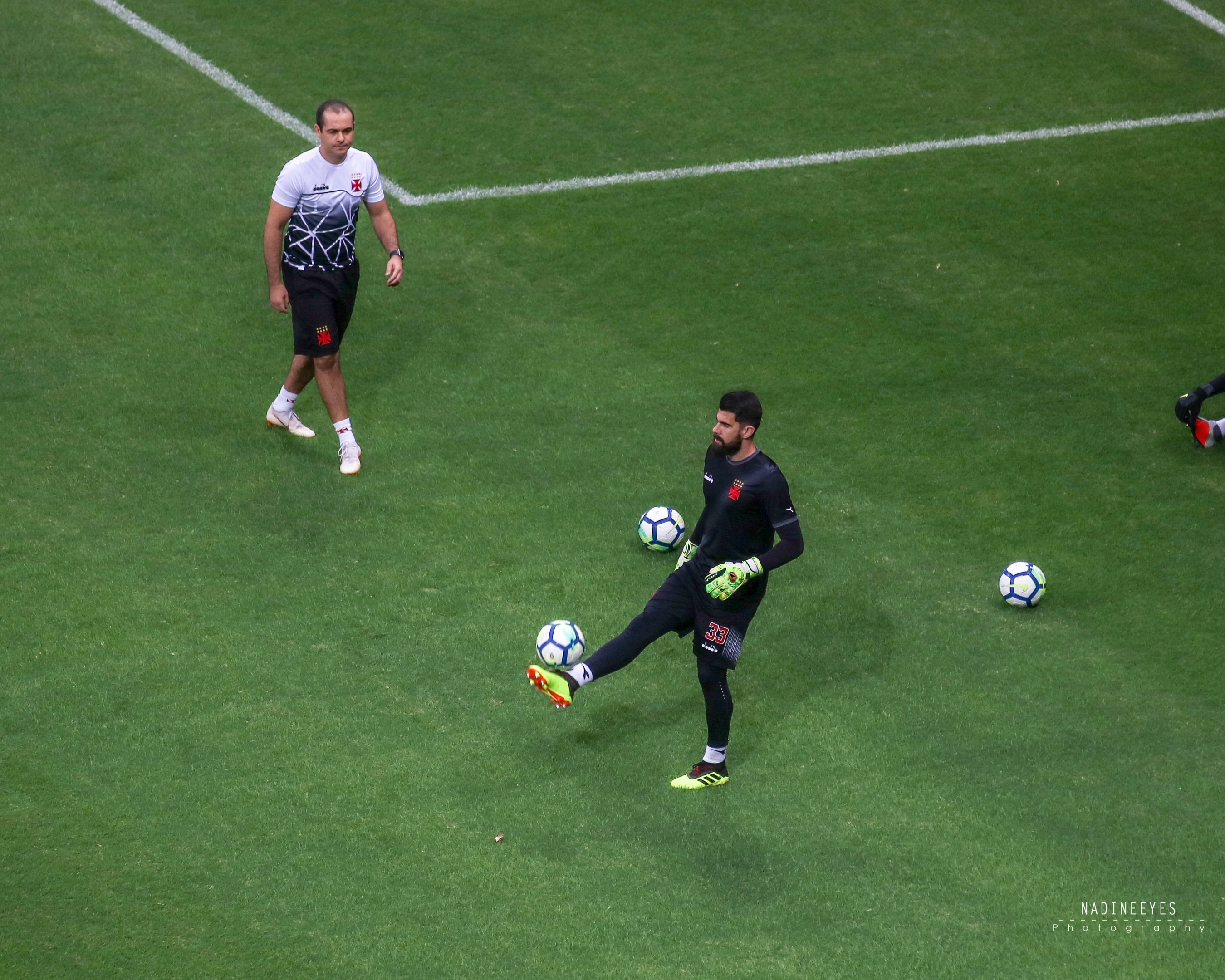 Ein professioneller Fußballspieler in einem Sportdress und -schuhen tritt einen Fußball auf einem saftig grünen Feld.