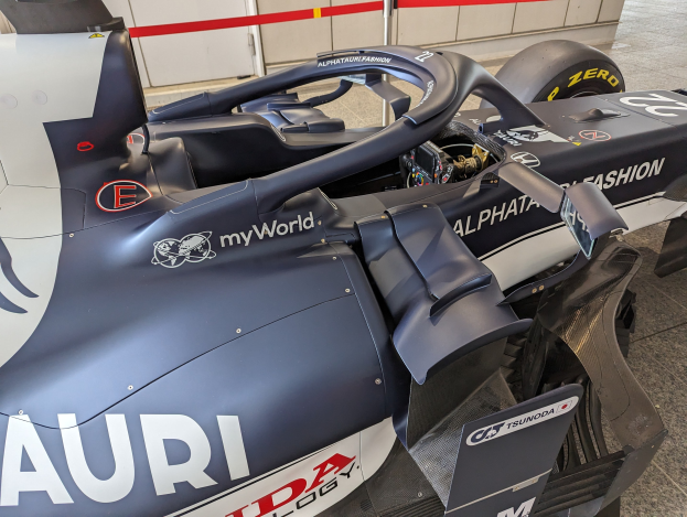 Ein Formel-E-Rennwagen in einem Museum ausgestellt, teilweise zusammengebaut mit Werkzeugen und Materialien drumherum, vor einer Wand im Hintergrund.