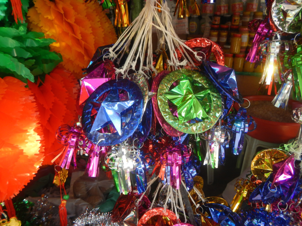 Bunte Festschmuckdekorationen, darunter Laternen und Bänder, hängen von der Decke über Regalen mit Flaschen im Hintergrund.
