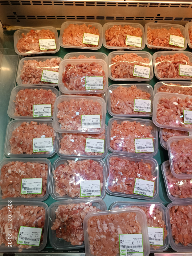 Gefrorenes Fleisch in Plastikbehältern mit Preisetiketten in einer Kühlvitrine.