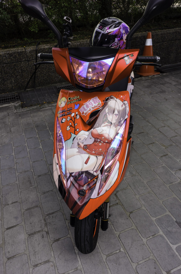 Oranges E-Scooter auf einer Straße mit Helm, einer Verkehrskegel, einer Wand und Bäumen im Hintergrund.