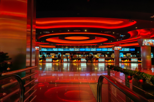 Ein Casino-Innenraum mit einem Weihnachtsbaum in der Mitte, gefliestem Boden, Geländern auf beiden Seiten, verzierten Säulen und Deckenlampen, mit Menschen im Hintergrund, die eine festliche Atmosphäre schaffen.