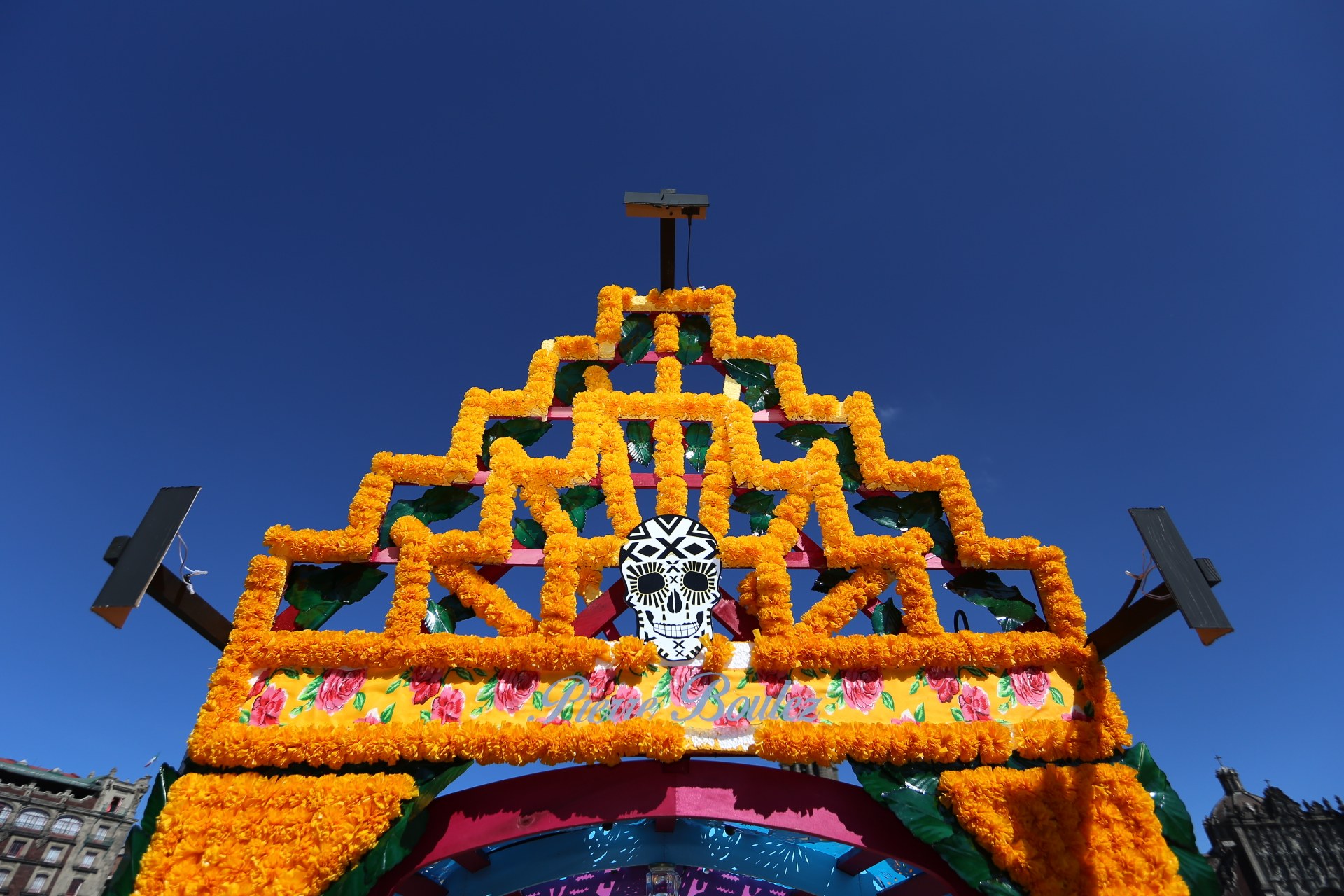 Ein Día de los Muertos-Bogen, geschmückt mit Blumen und einem Schädel in Mexiko-Stadt, vor einem klaren blauen Himmel.