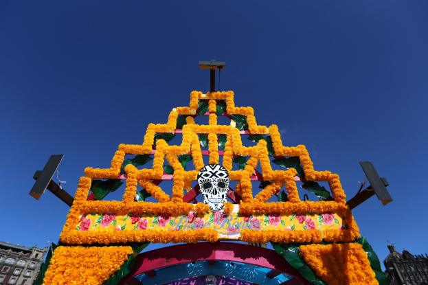 Ein Día de los Muertos-Bogen, geschmückt mit Blumen und einem Schädel in Mexiko-Stadt, vor einem klaren blauen Himmel.