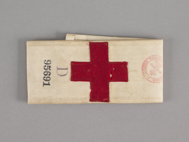 Ersthilfekoffer mit einem roten Kreuzsymbol auf einer Stofftasche, die auf einer Oberfläche liegt.