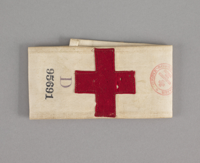 Ersthilfekoffer mit einem roten Kreuzsymbol auf einer Stofftasche, die auf einer Oberfläche liegt.