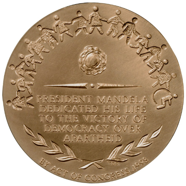 Goldene Medaille mit der Inschrift "Präsident Mandela widmete sein Leben dem Sieg der Demokratie über die Apartheid" vor einem weißen Hintergrund.