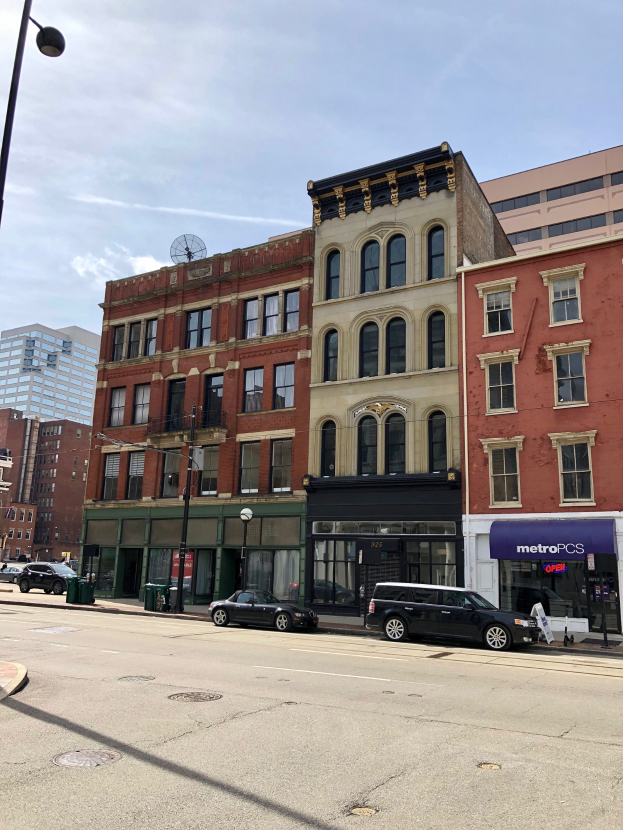 Stadtstraße mit parkenden Autos, Laternenmasten, Mülltonnen und Gebäuden unter einem bewölkten Himmel, mit einem gewerblichen Immobilienangebot an 715 N Main St, Chicago, IL 60611.