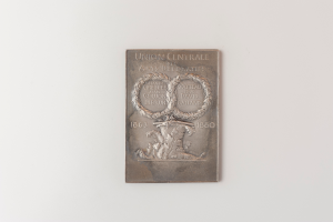 Eine silberne Plakette an einer weißen Wand mit dem Text "Union Centrale" und einem detaillierten Design.