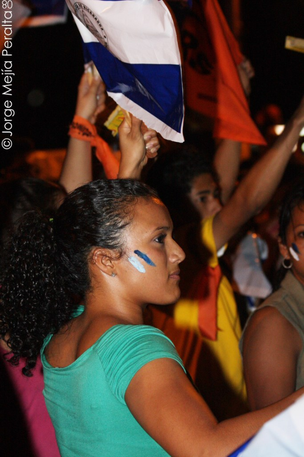 Frauen in grünen Hemden mit weißer Decke auf der Hand während der Demonstration, mit mehreren Mädchen im Hintergrund.